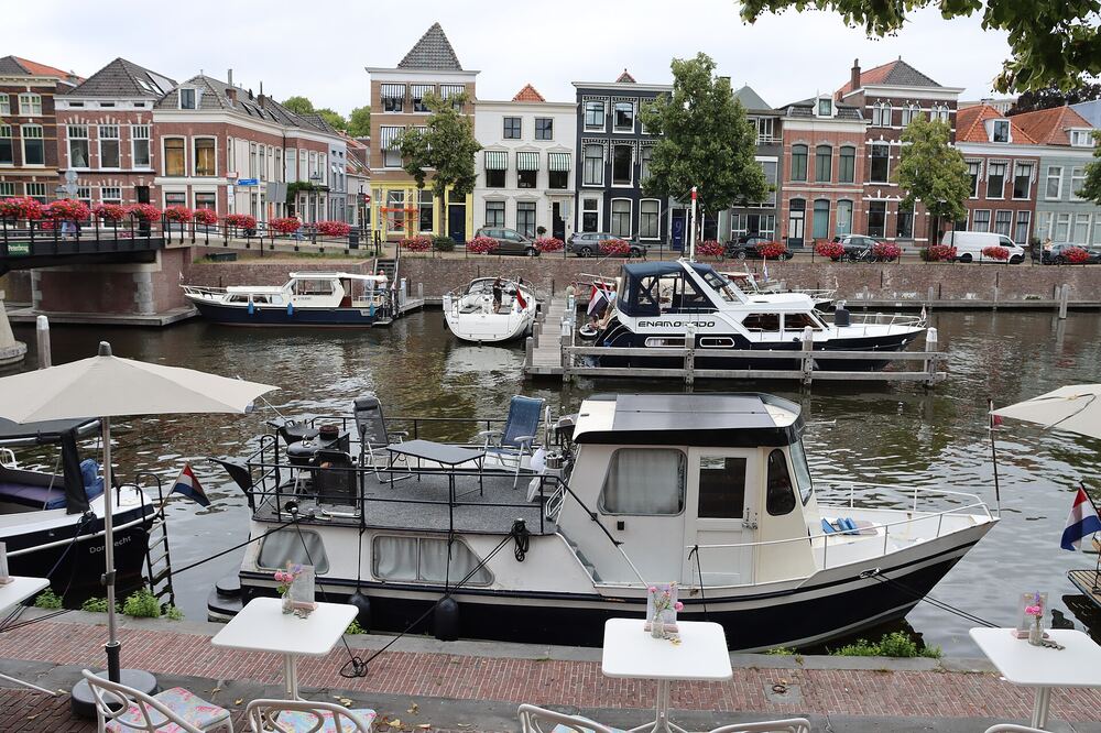 De Lingehaven in Gorinchem met aangemeerde boten, historische trapgevels langs de kade en bloembakken op de brug